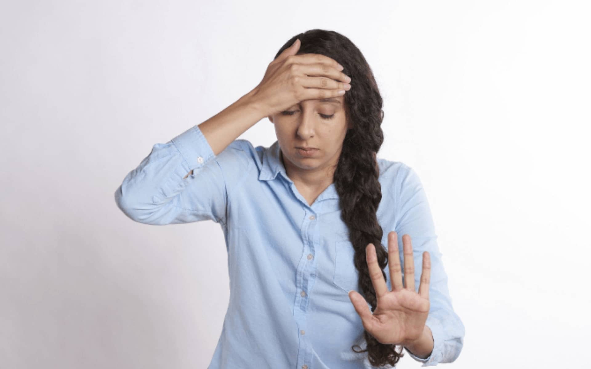 Woman overwhelmed holding forehead and showing wait gesture